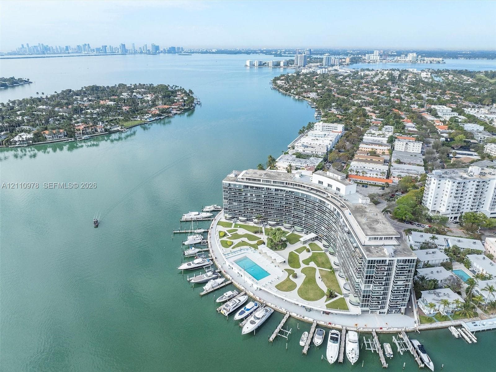 Waterfront property featuring a private marina with deep-water boat slips, a swimming pool, manicured lawn areas, and a multi-story residential building