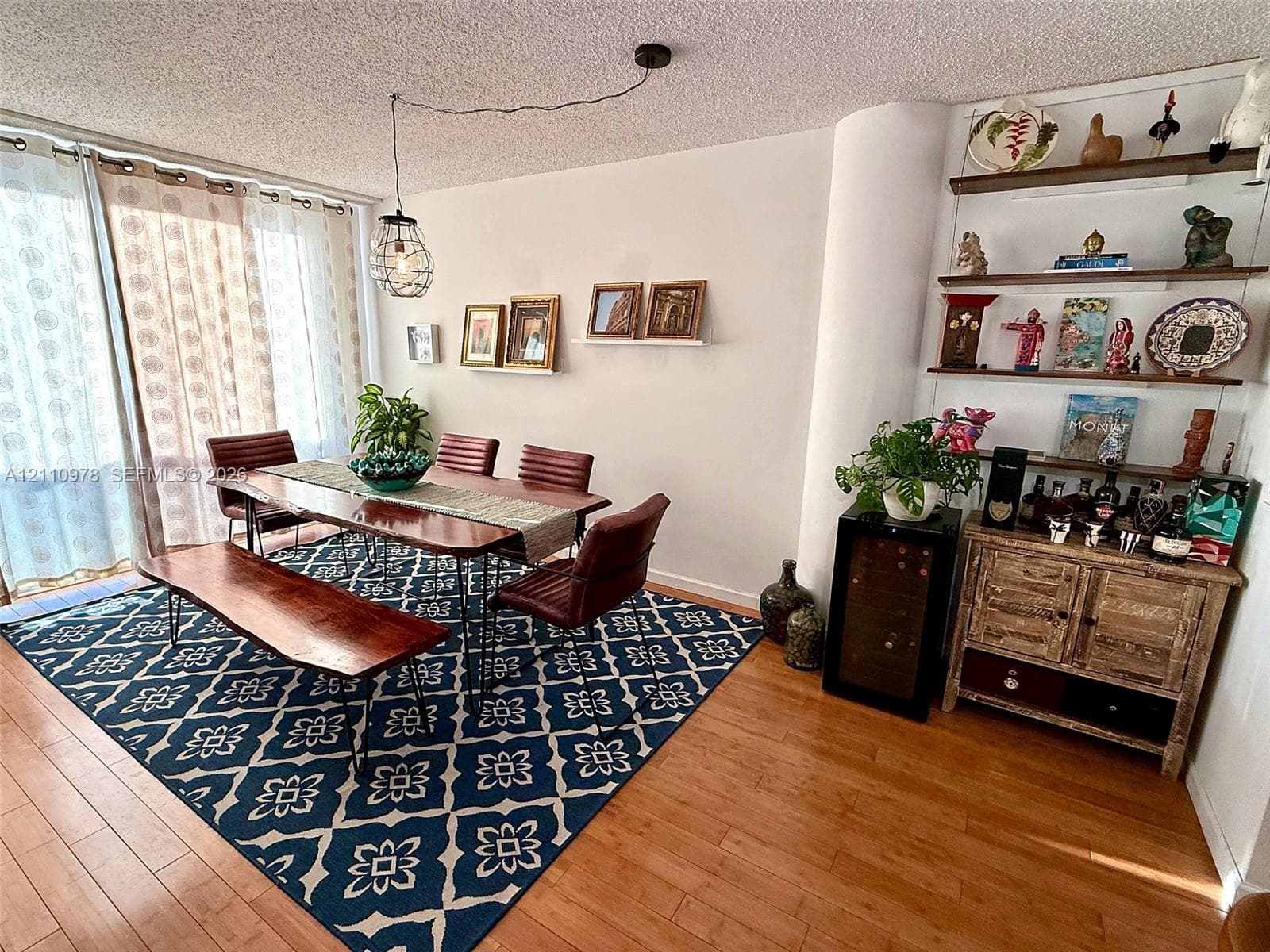 Living area featuring wood-finish flooring, floor-to-ceiling glass sliding doors, built-in recessed shelving, and a decorative pendant light