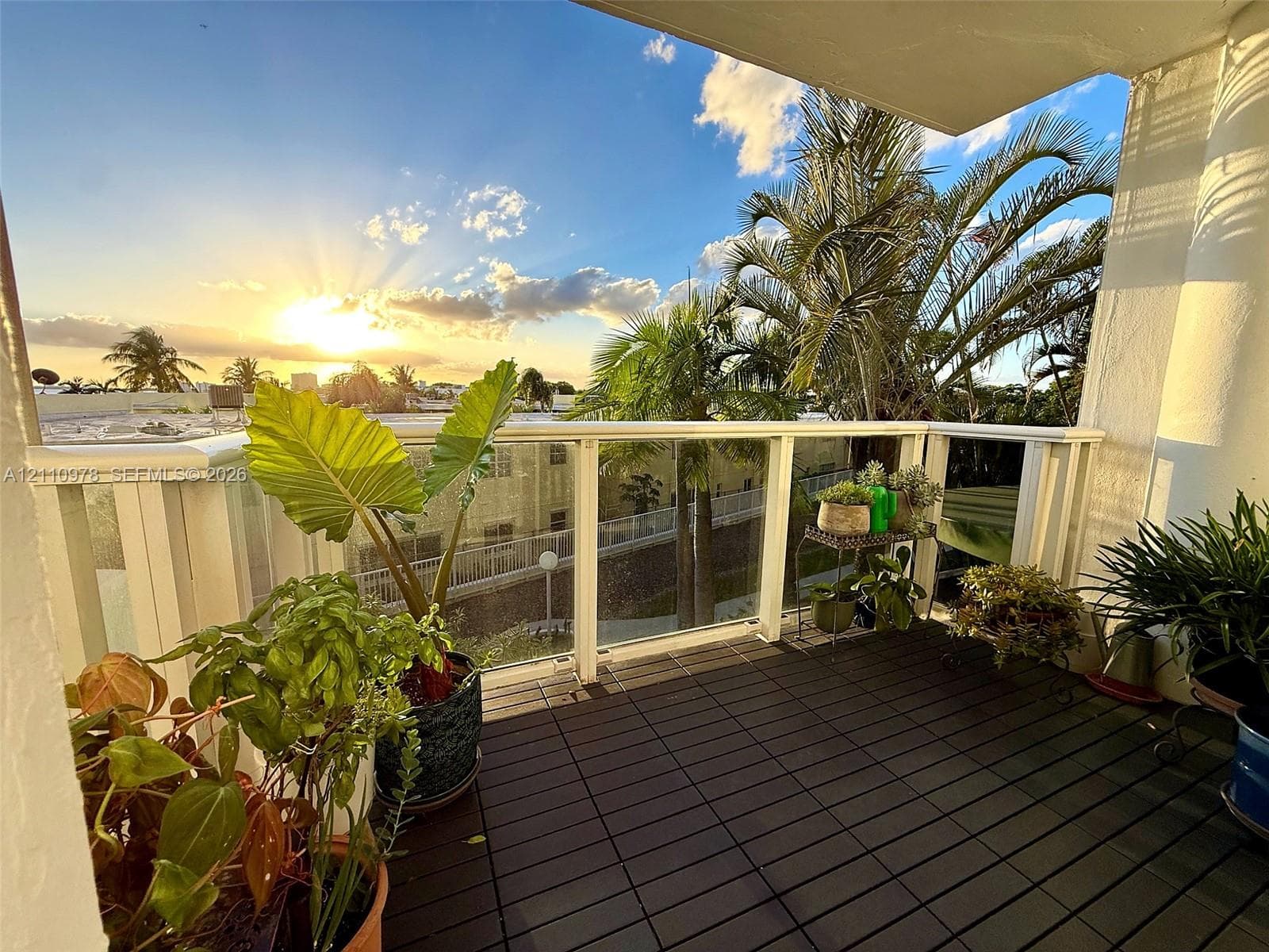 Private balcony featuring interlocking deck tiles and a glass-paneled railing
