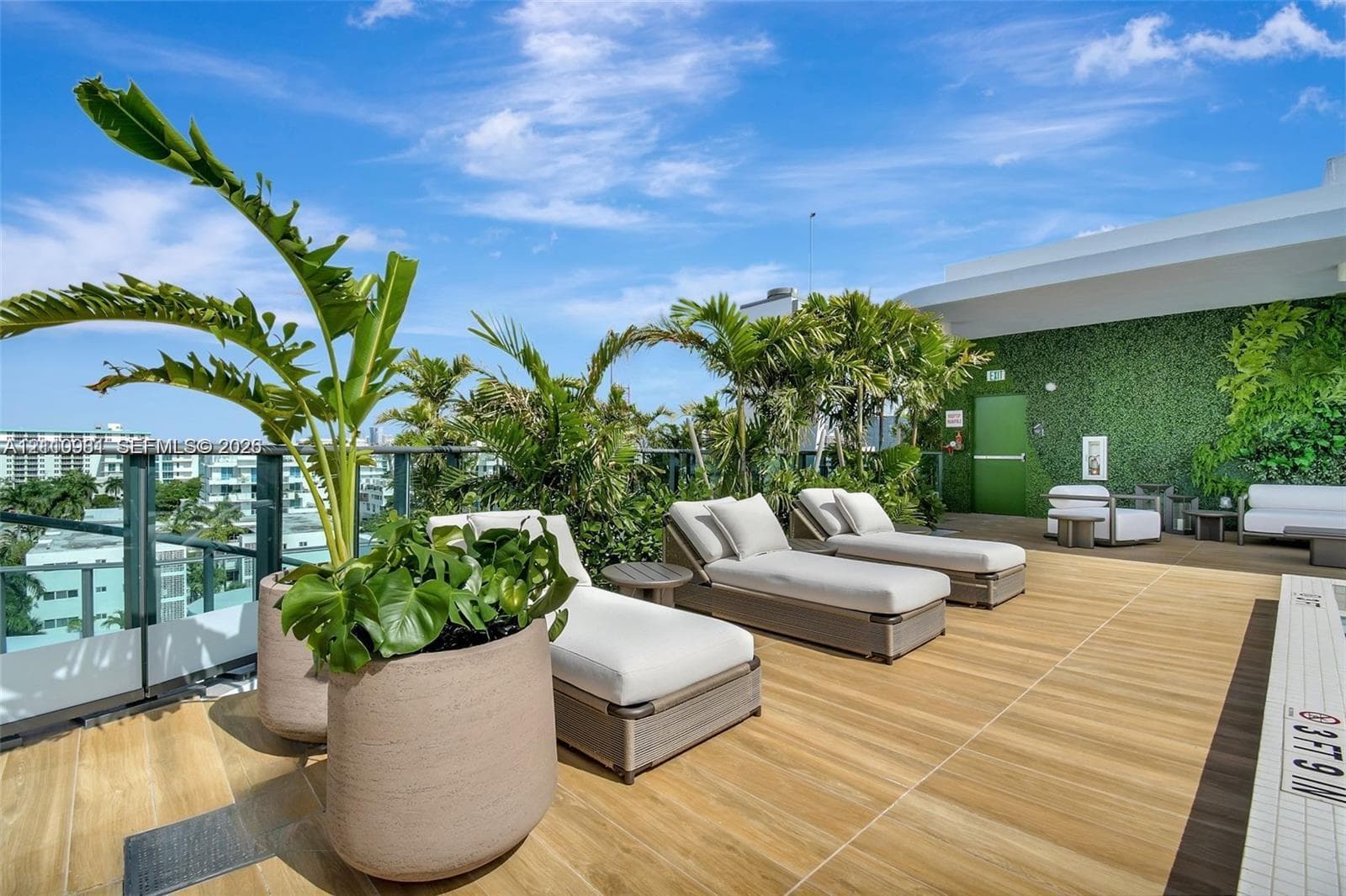 Rooftop terrace featuring wood-finish tile flooring, glass panel railings, and a green wall accent