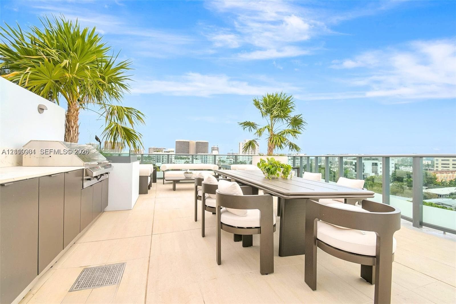 Rooftop terrace featuring large-format tile flooring, built-in stainless steel grill, minimalist cabinetry, and glass panel perimeter railing