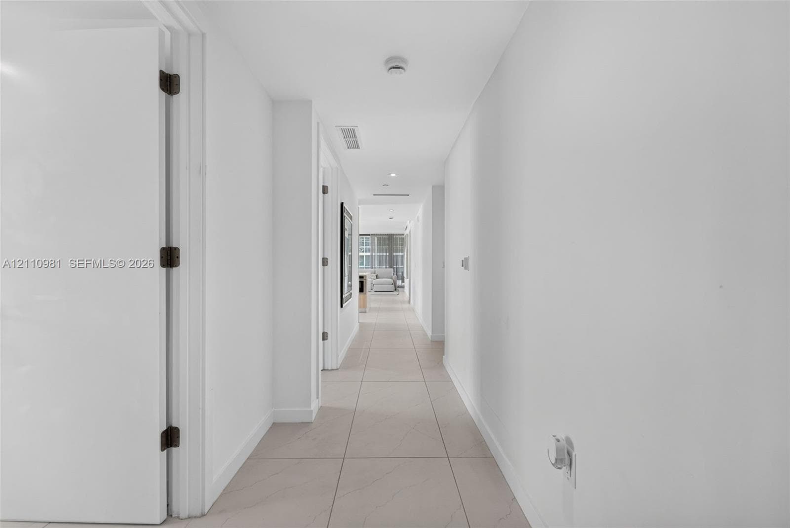 Hallway featuring large-format rectified tile flooring, smooth-finish ceilings, and recessed lighting
