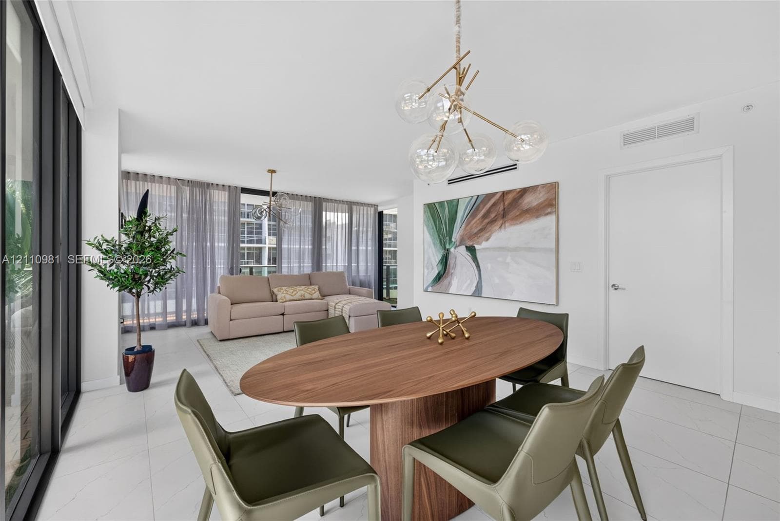 Open-concept interior featuring large-format tile flooring, floor-to-ceiling glass wall, and a multi-globe branching chandelier