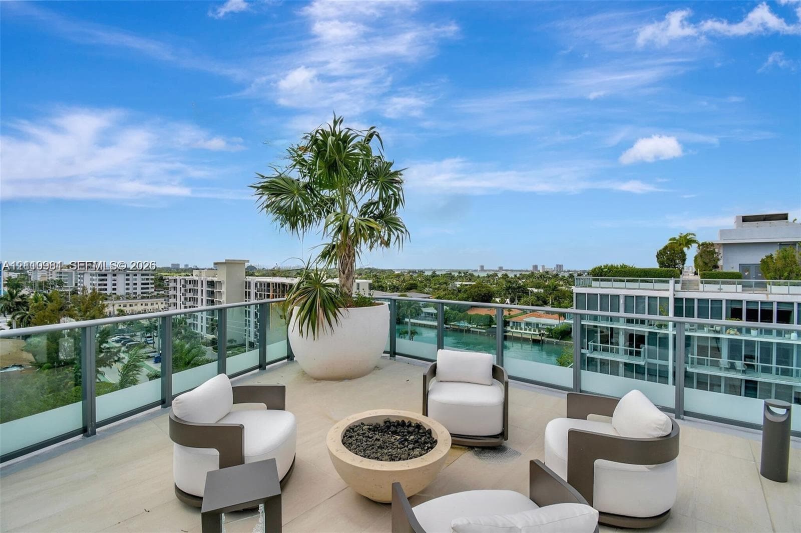 Spacious terrace featuring light-toned tile flooring, glass panel railings, and a circular fire pit