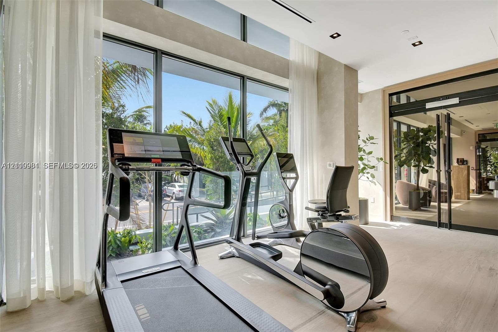 Floor-to-ceiling glass windows, recessed ceiling lighting, wood-finish flooring, and minimalist glass-paneled doors