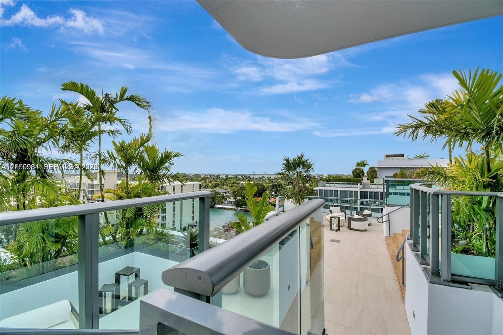 Expansive rooftop terrace featuring porcelain tile flooring, glass panel railings, and perimeter landscaping