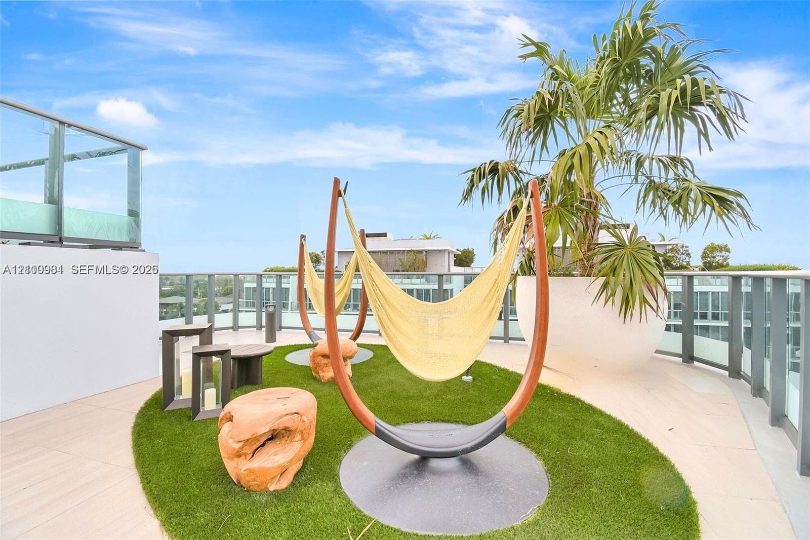 Rooftop terrace featuring large-format tile flooring, glass panel railings, and a synthetic turf inlay