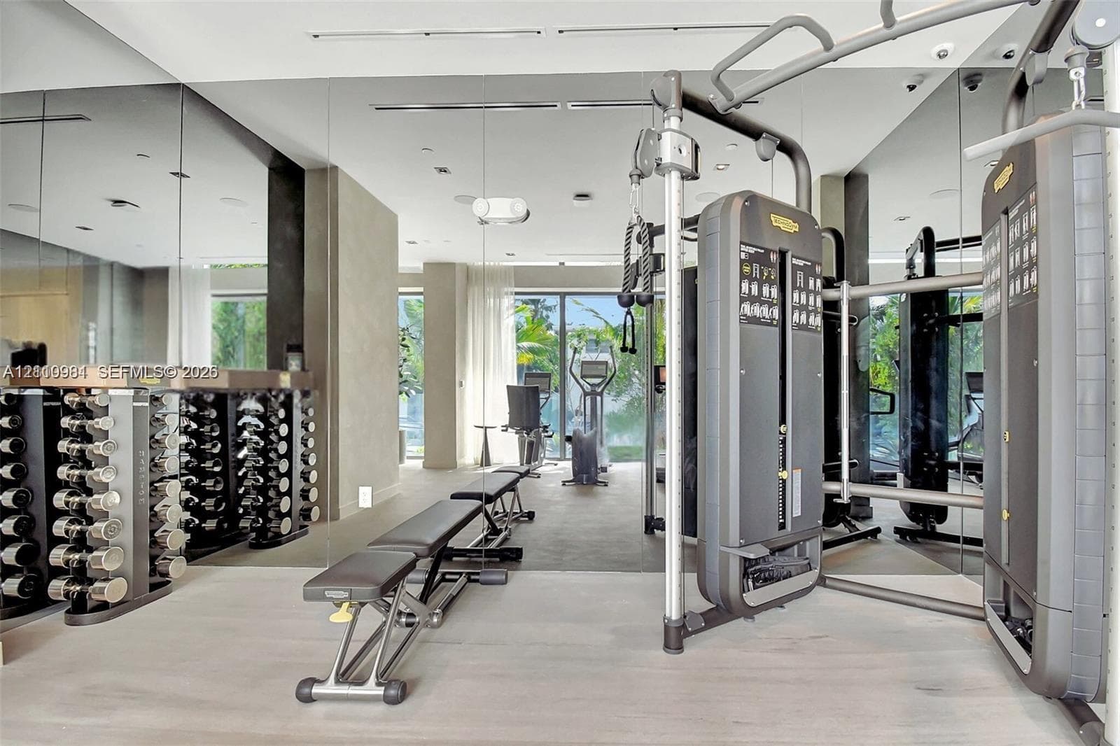 Fitness area featuring expansive floor-to-ceiling mirrors, neutral-toned flooring, recessed ceiling lighting, and large glass pane windows