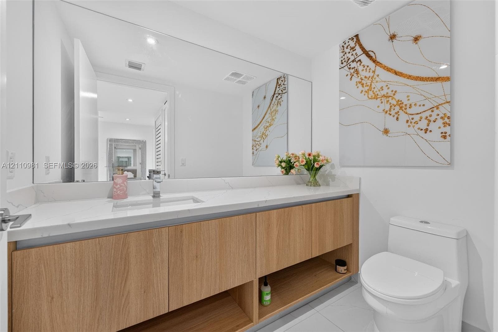Floating wood-finish vanity with an integrated lower display shelf, white surface countertop, undermount sink, and full-width vanity mirror