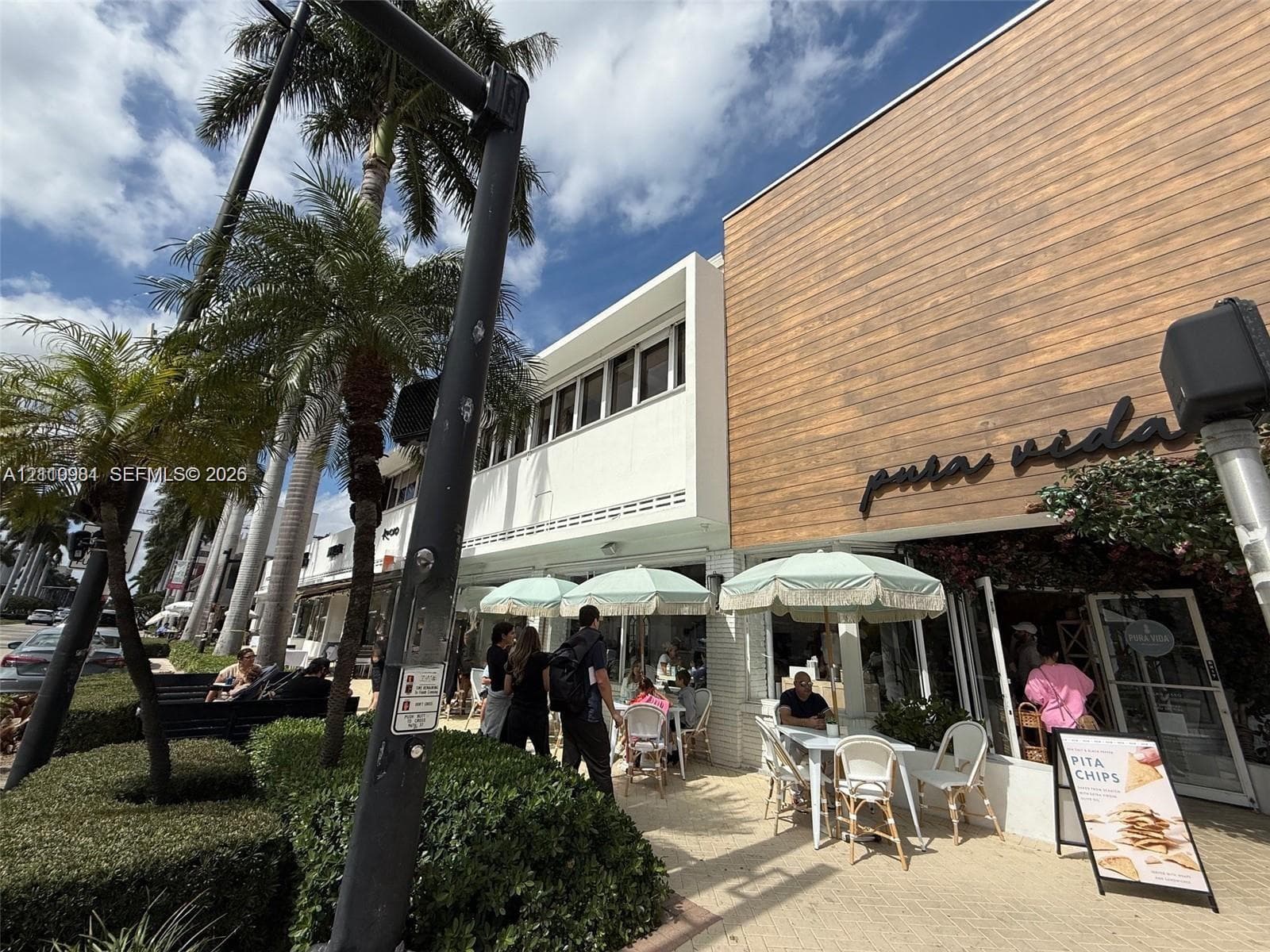 Commercial storefront exterior featuring wood-finish paneling, white masonry facade, and an outdoor patio space