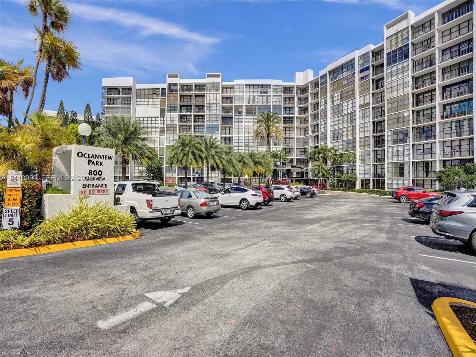 Multi-story residential complex featuring glass-paneled balconies and exterior signage