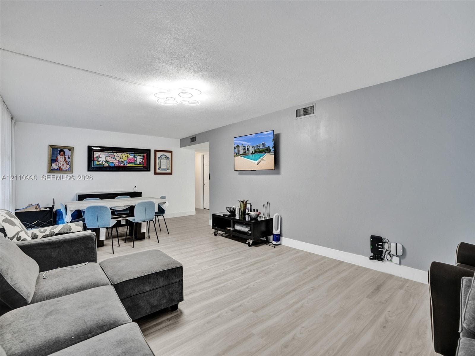 Open-concept interior featuring wood-finish flooring, neutral wall tones, and modern circular flush-mount ceiling lighting