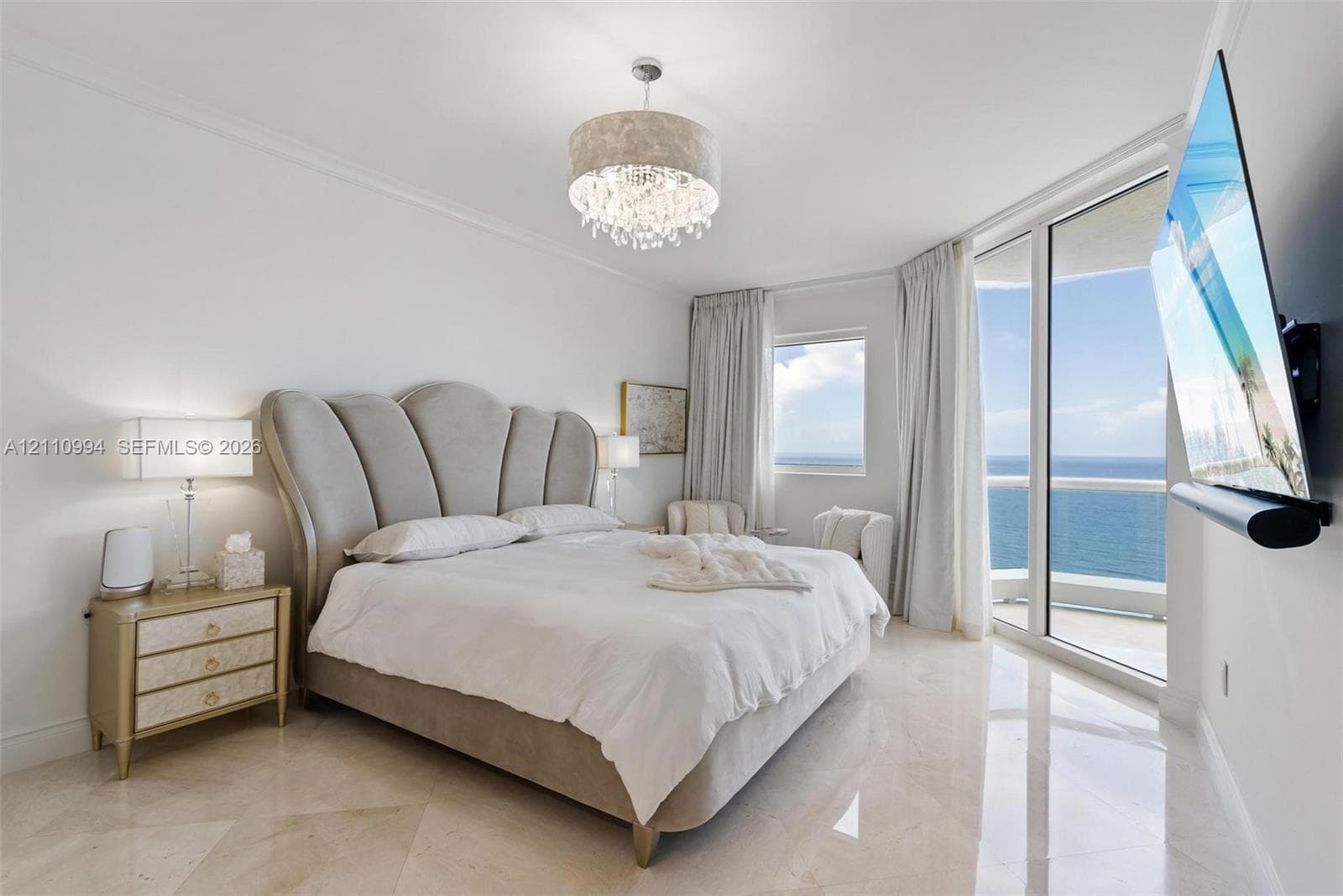 Polished tile flooring, floor-to-ceiling glass paneling, balcony access, and an ornate drum-style chandelier
