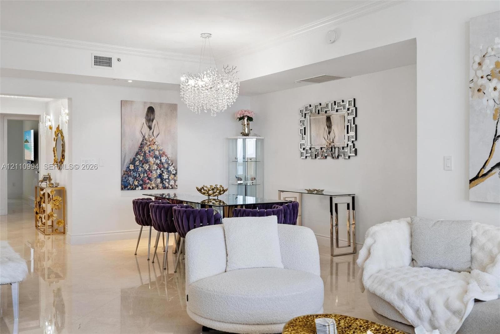 Polished stone flooring, intricate crystal statement chandelier, crown molding, and recessed wall niche