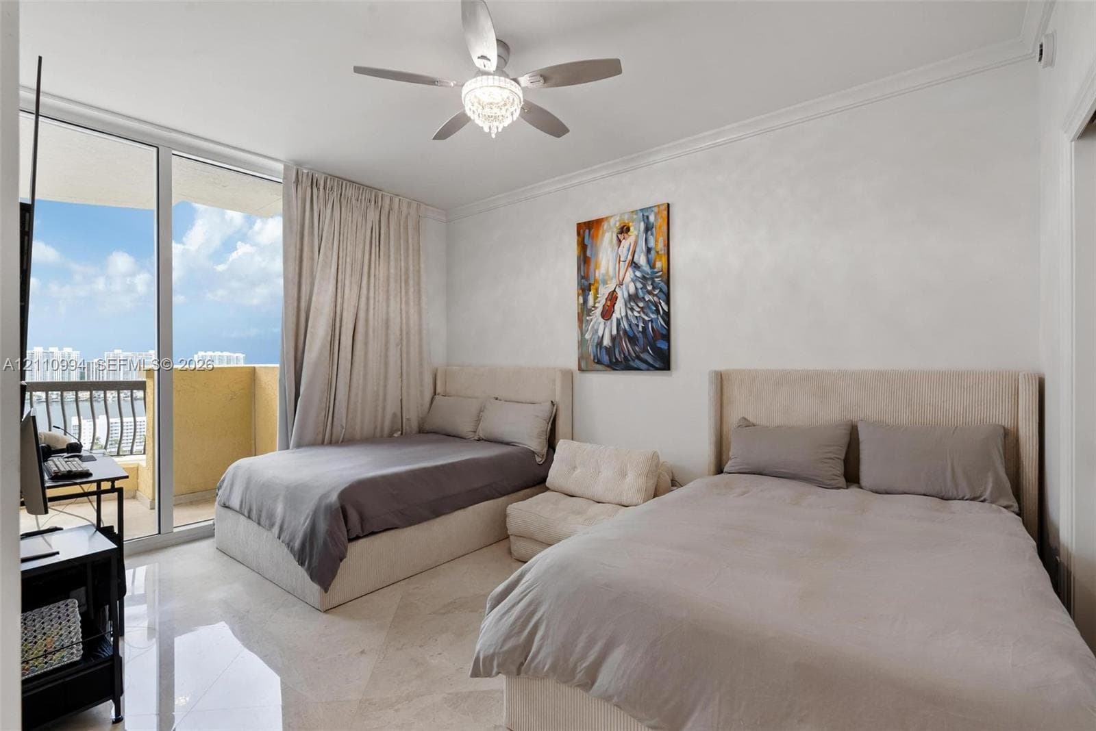 Floor-to-ceiling glass sliding doors opening to a balcony, polished stone flooring, crown molding, and a central ceiling fan with an integrated light fixture