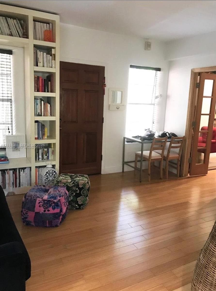 Built-in floor-to-ceiling shelving, wood-finish flooring, solid wood entry door, and multi-pane wood-frame glass door