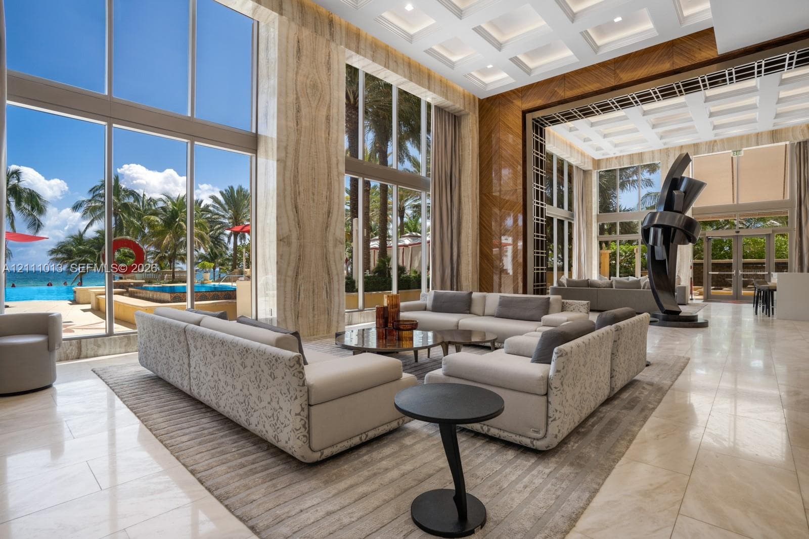 Double-height floor-to-ceiling windows, coffered ceilings, stone wall cladding, polished tile flooring, and integrated recessed lighting