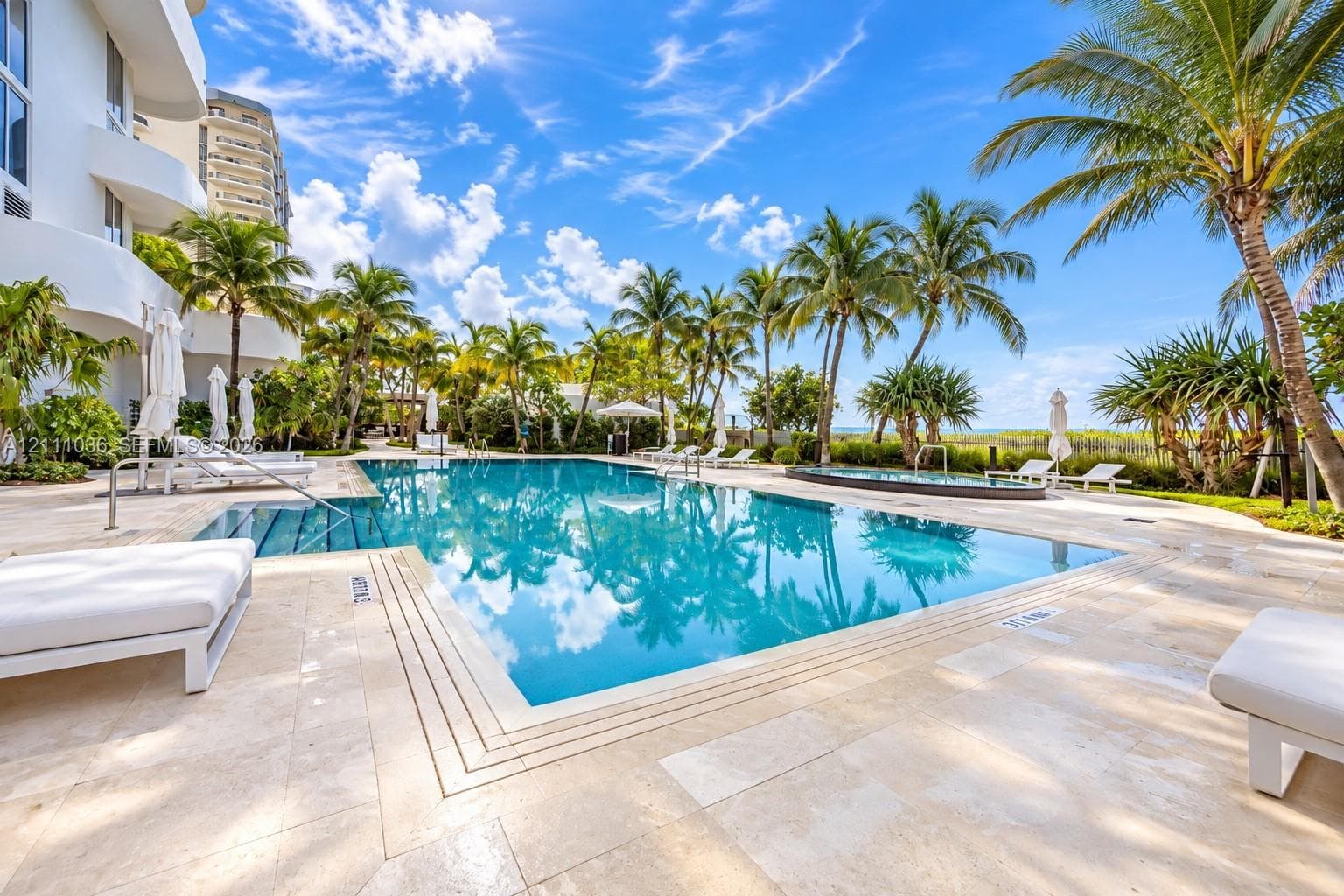 Swimming pool with stone-tiled deck, integrated spa, and surrounding palm trees