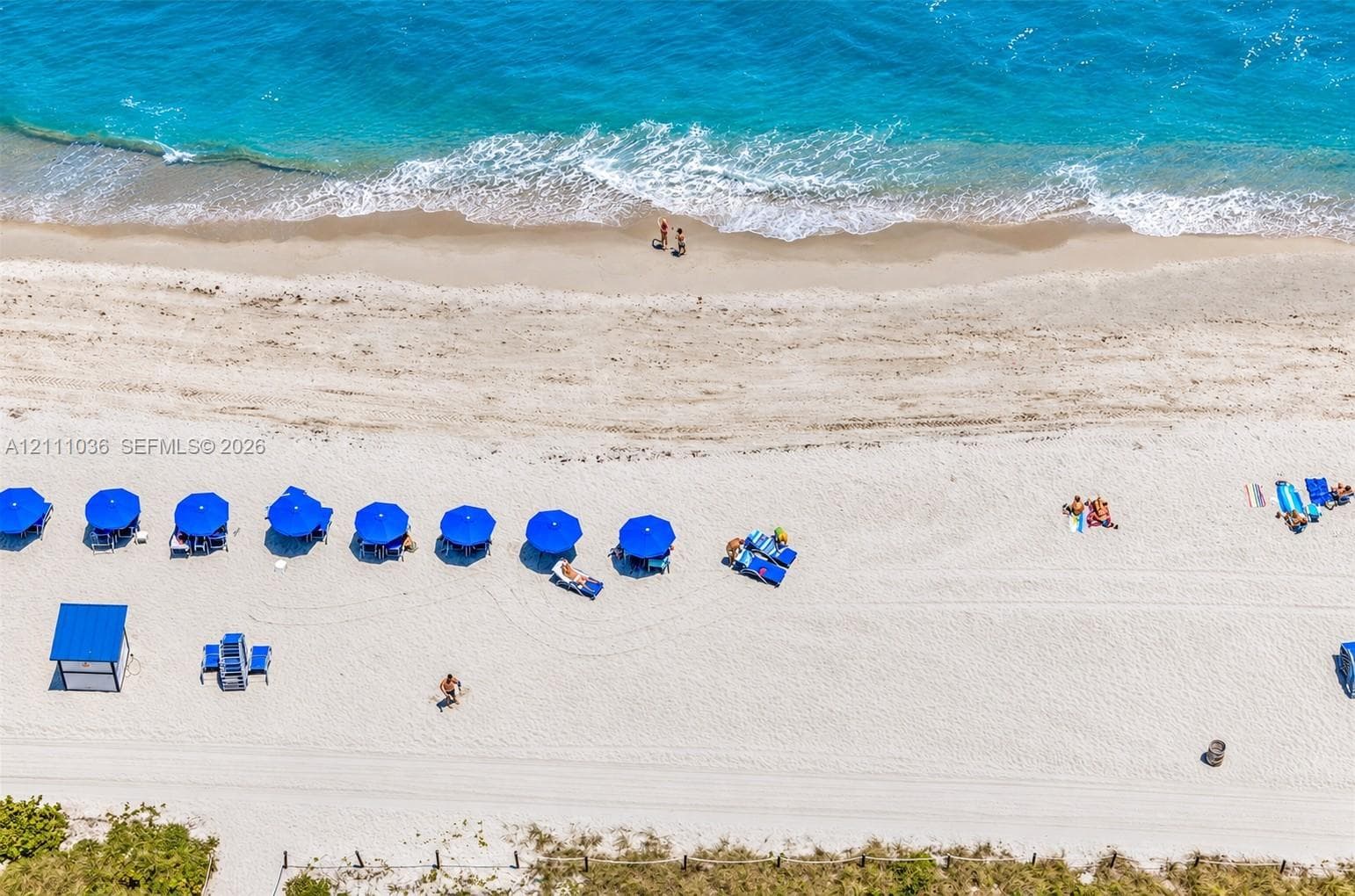 Direct oceanfront access featuring expansive sandy shoreline, turquoise water, and professional hardscaping