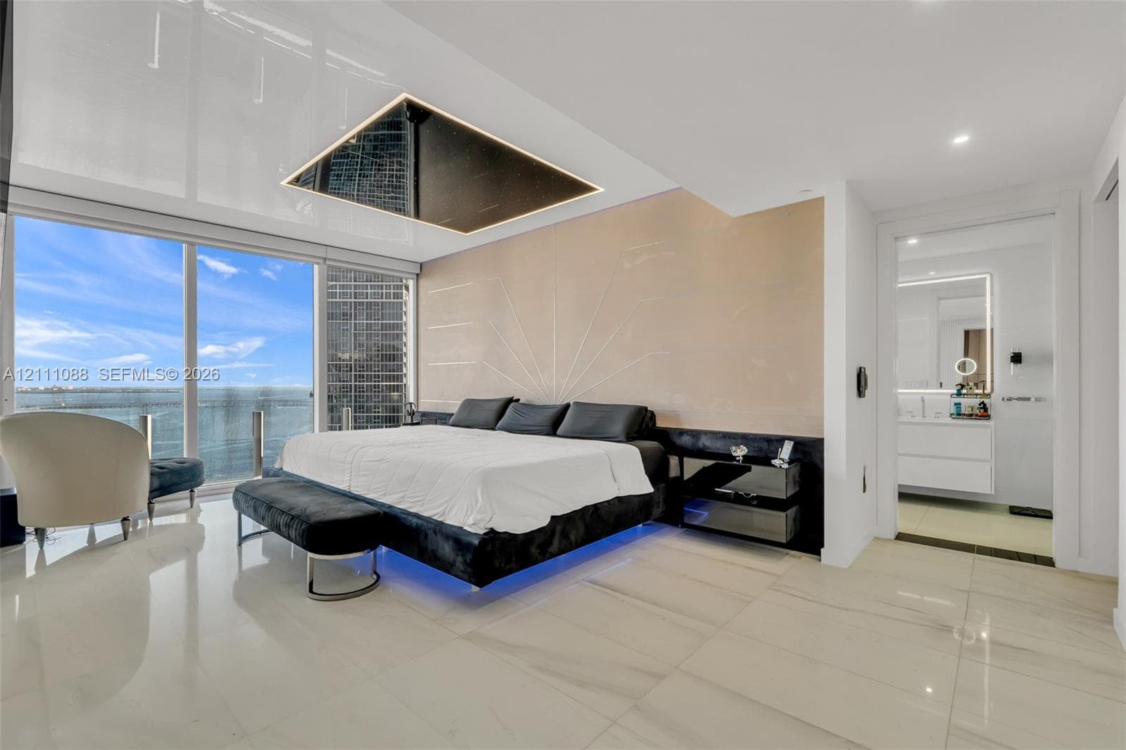 Floor-to-ceiling glass windows, recessed ceiling feature with integrated lighting, custom wall detailing, stone-finish flooring, and built-in vanity