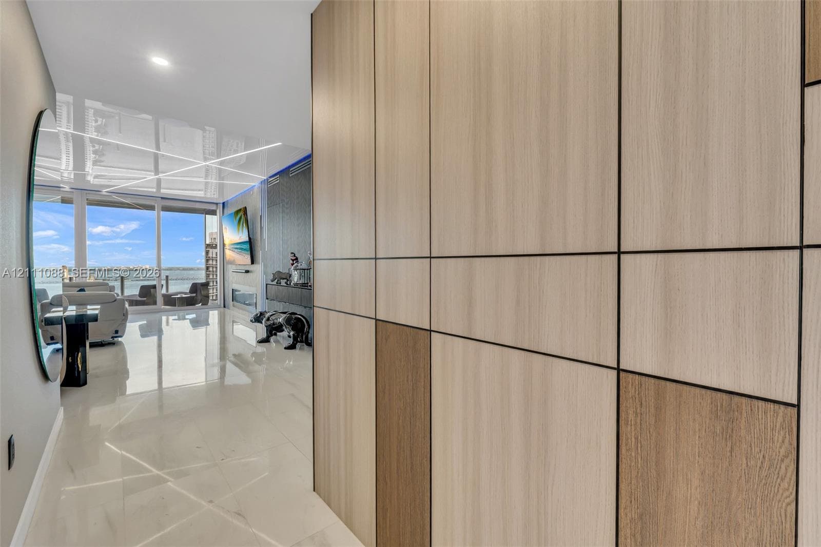 Floor-to-ceiling multi-tonal wood-finish paneling with integrated reveals, polished stone-finish flooring, and expansive floor-to-ceiling glass sliding doors