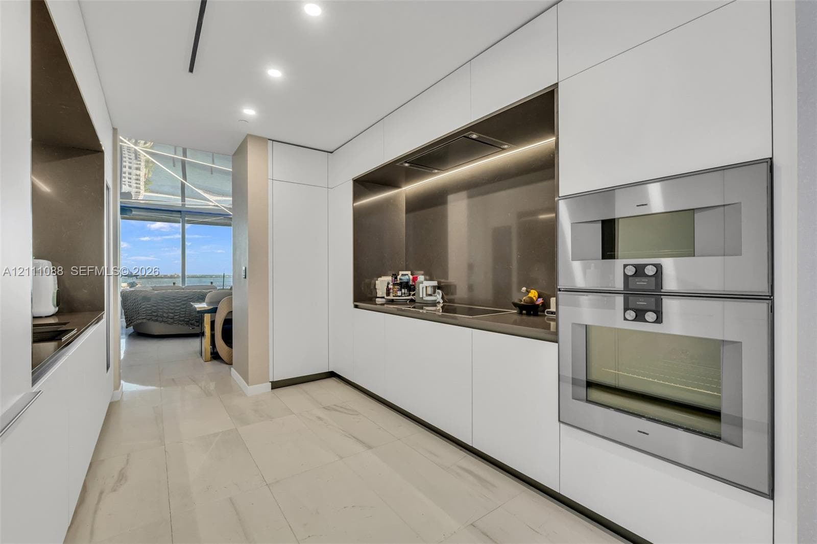 Sleek kitchen featuring floor-to-ceiling cabinetry, integrated stainless steel double wall ovens, recessed lighting, and solid-surface countertops
