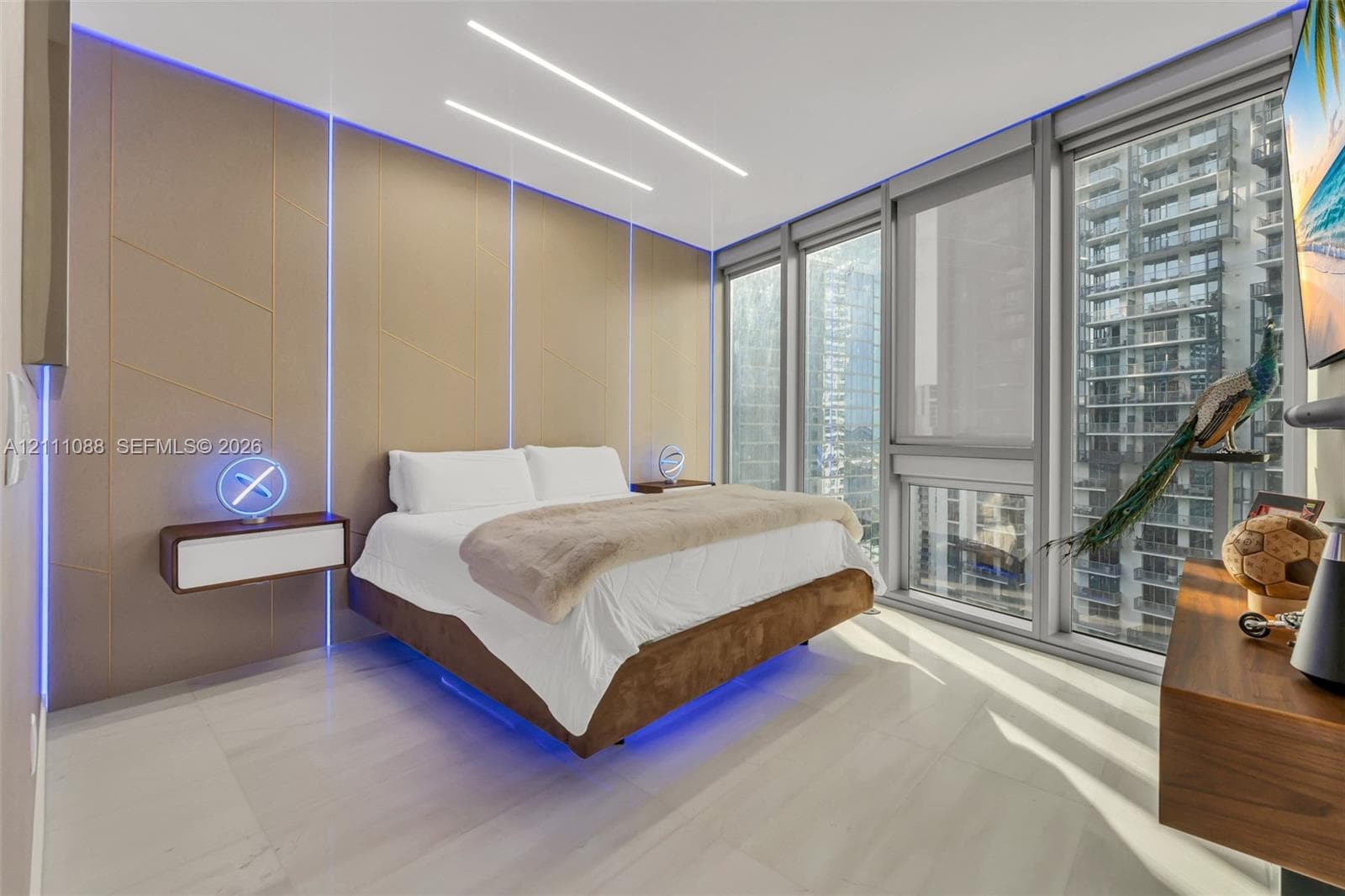 Floor-to-ceiling windows, custom paneled accent wall with integrated LED lighting, floating built-in bedside storage, and high-gloss tile flooring