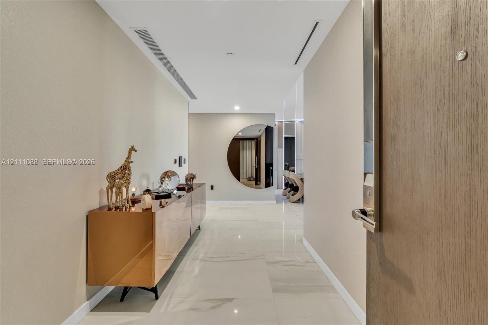 Entryway featuring neutral wall finishes, large-format polished tile flooring, recessed ceiling lighting, and a circular wall mirror