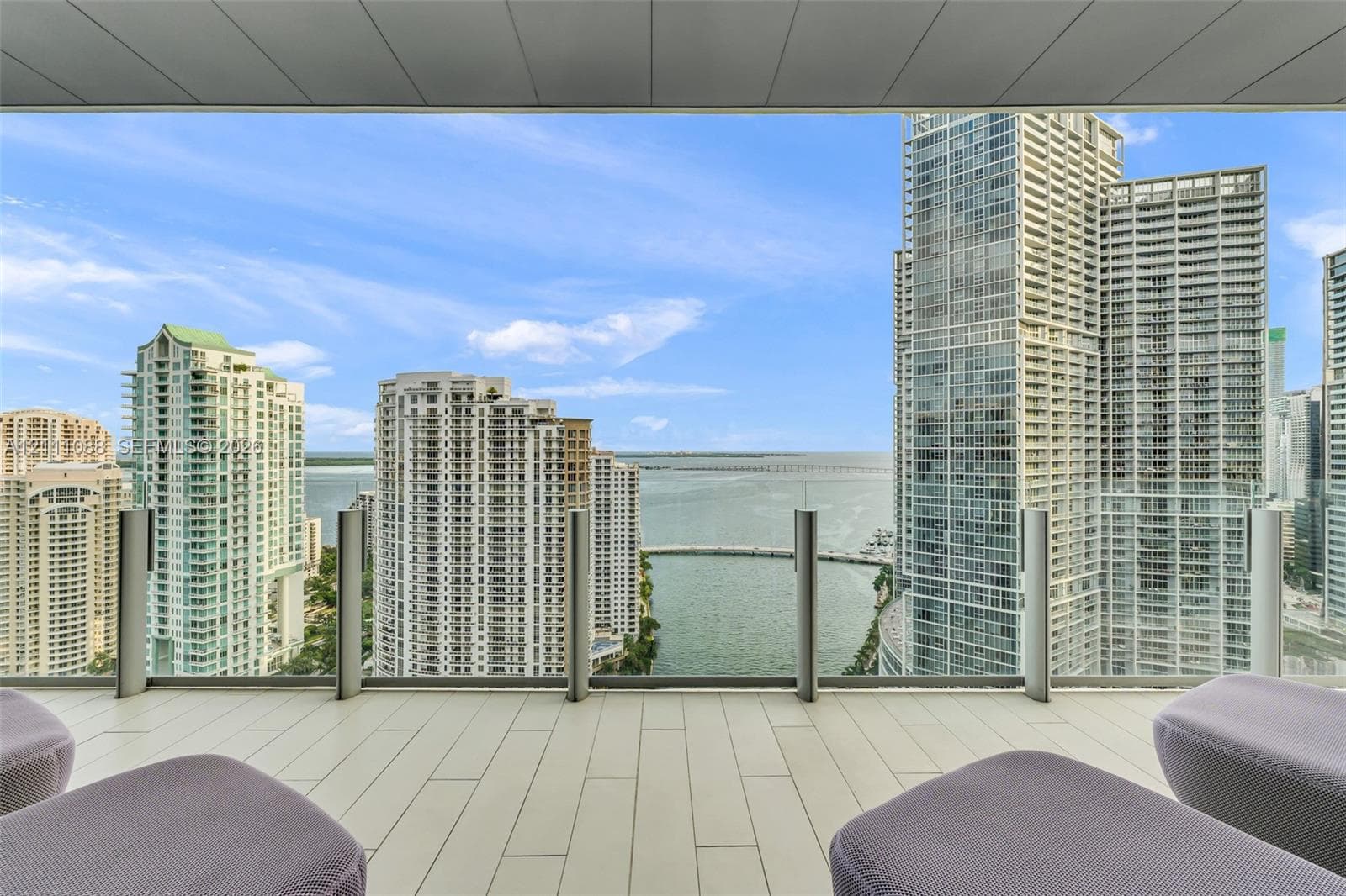 Covered balcony featuring oversized tile flooring and a transparent glass panel railing