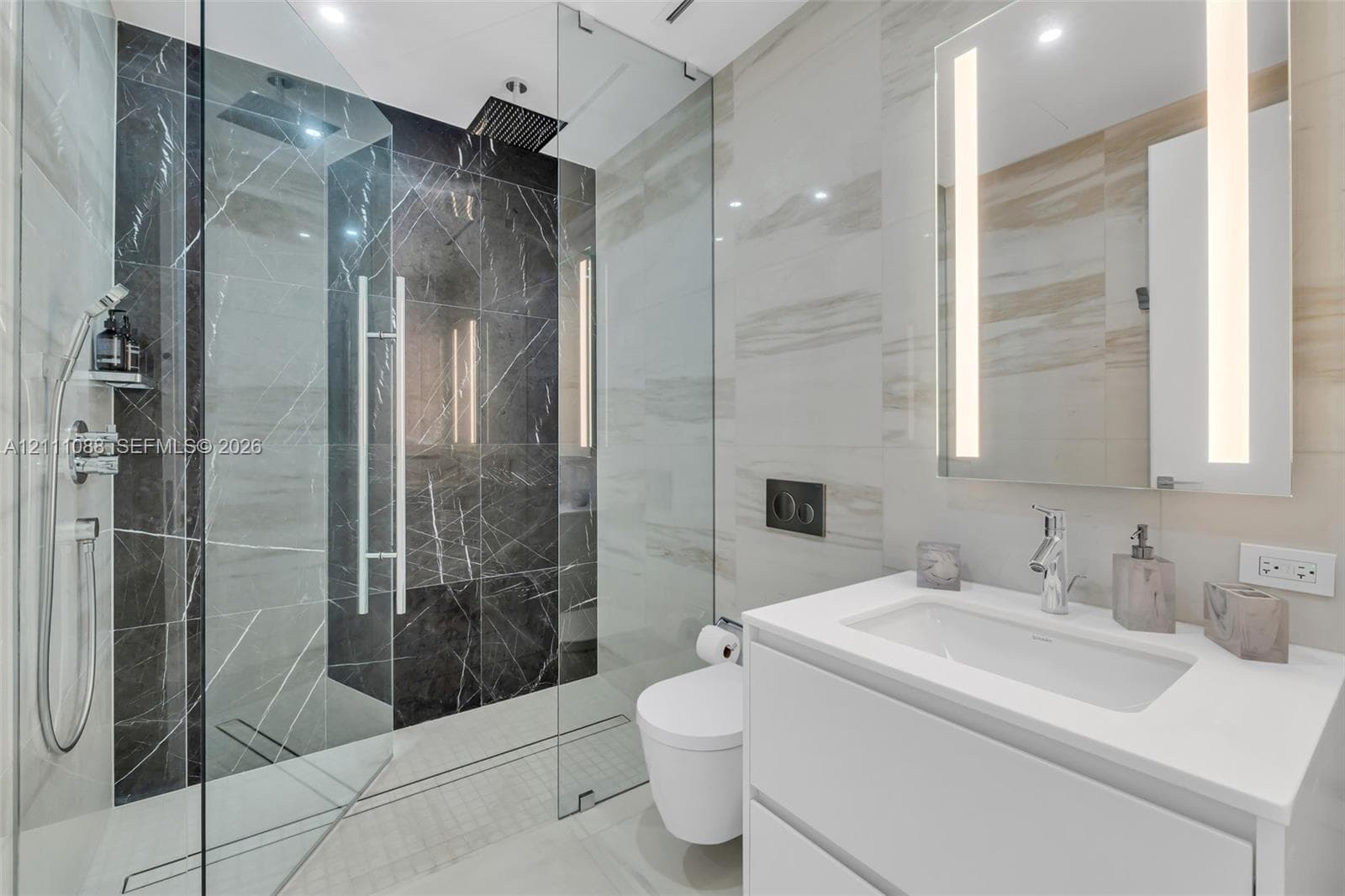 Walk-in shower featuring glass enclosure, rain-style showerhead, and dual-toned tile surround