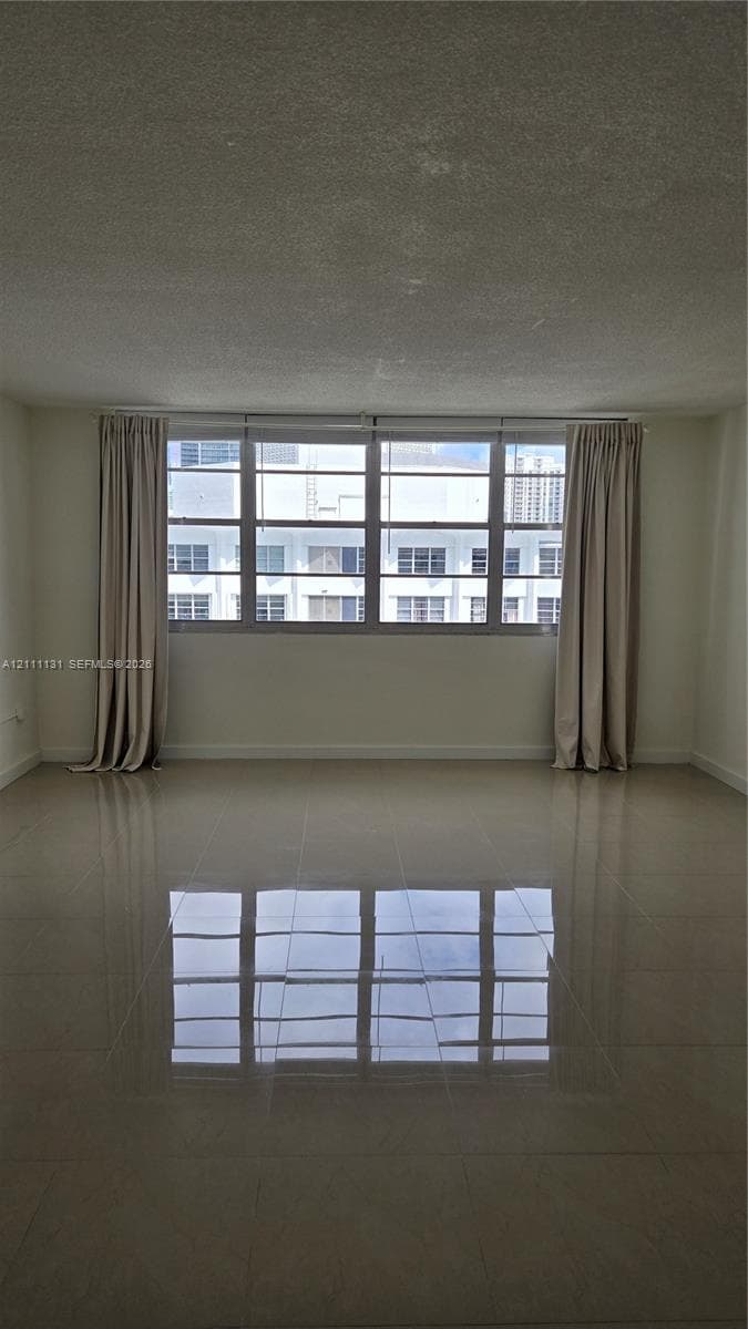 Large living area featuring polished tile flooring, neutral wall tones, and expansive multi-pane windows