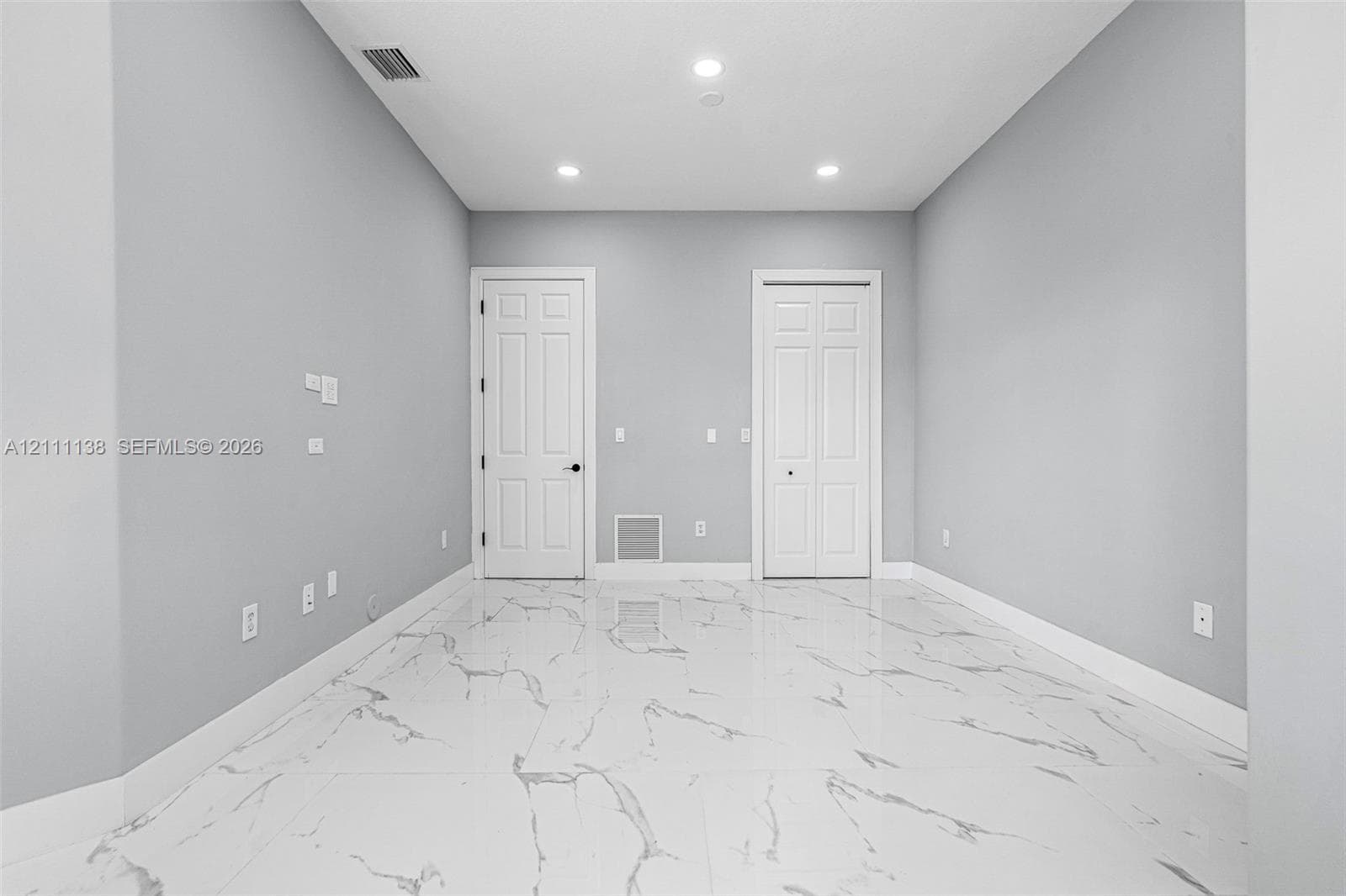 Neutral-toned interior featuring large-format stone-patterned tile flooring, recessed lighting, and white panel doors