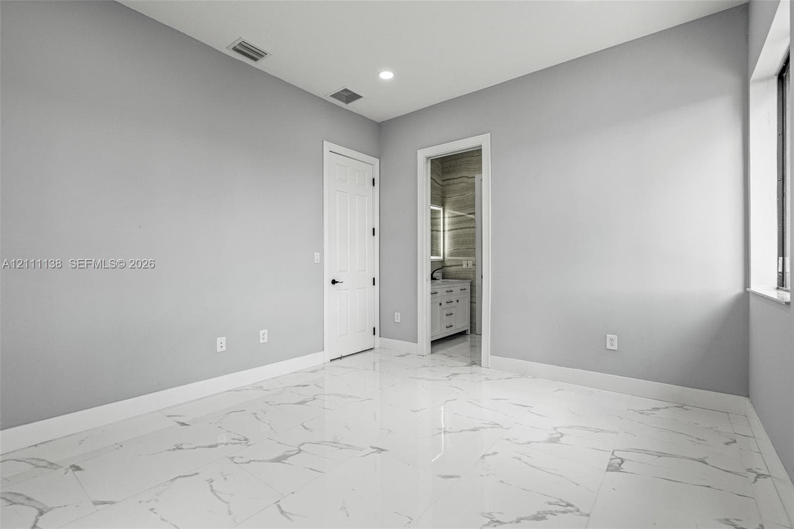 Polished stone-finish flooring with large-format veining, recessed lighting, and a multi-panel door