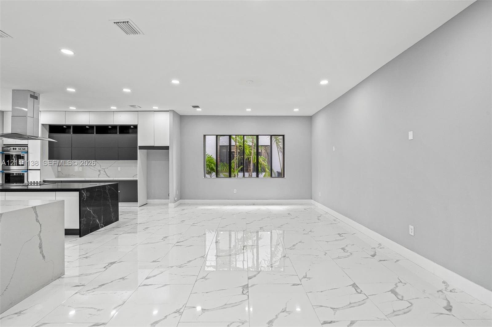 Open-concept interior featuring large-format polished stone-finish flooring, two-tone cabinetry with contrasting stone-finish countertops, stainless steel wall oven, and recessed lighting