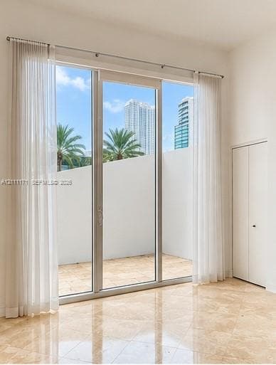 Floor-to-ceiling glass sliding doors, polished stone tile flooring, and a private terrace with a concrete wall surround