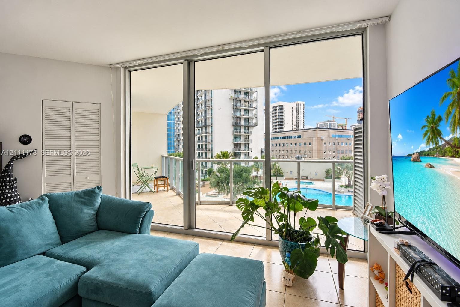 Floor-to-ceiling sliding glass doors, tile flooring, and an expansive balcony with metal railing