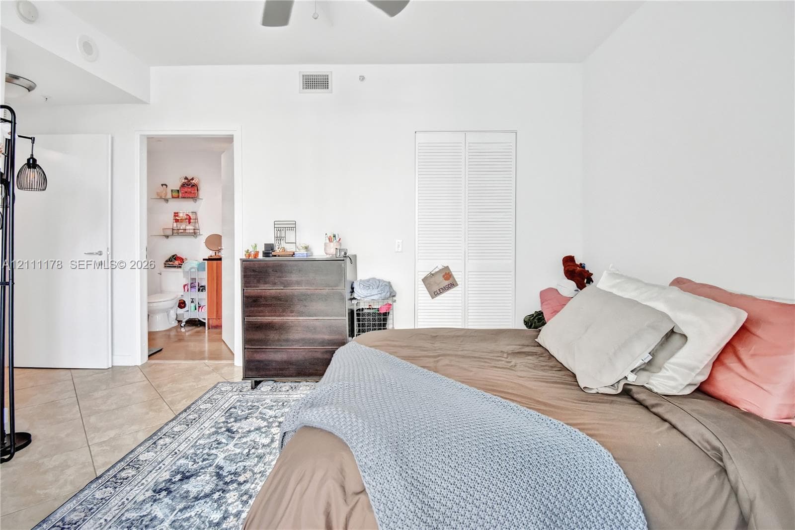 Room featuring tile flooring, ceiling fan, and white louvered closet doors