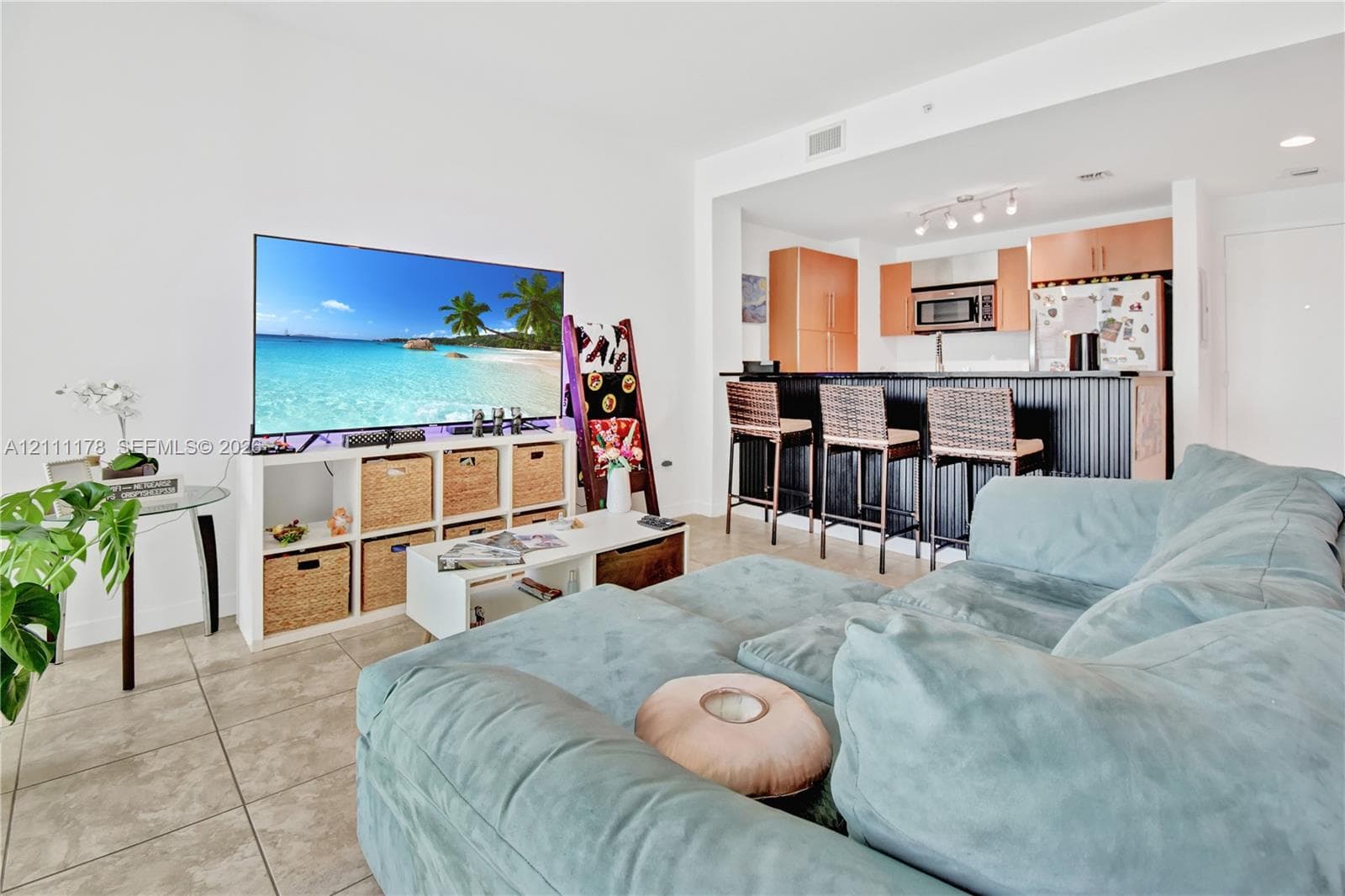Open-concept kitchen featuring wood-finish cabinetry, a high-top breakfast bar with dark paneling, built-in microwave, and tile flooring