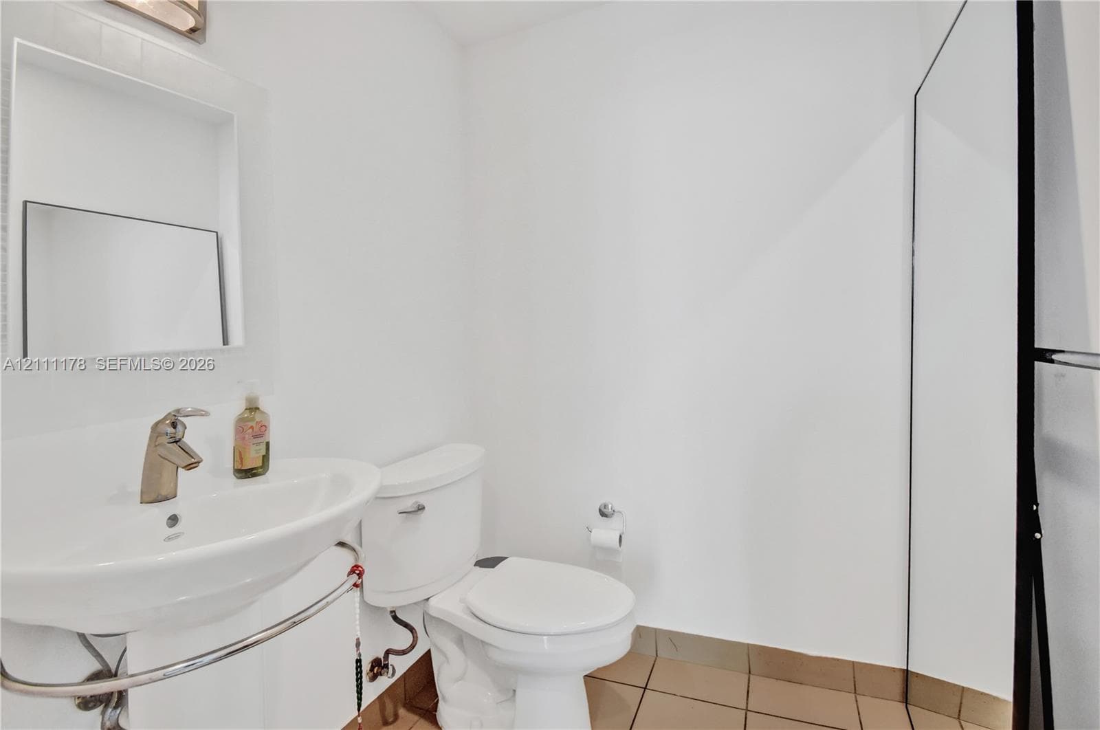 Pedestal sink with chrome faucet, recessed medicine cabinet, white toilet, and tile flooring