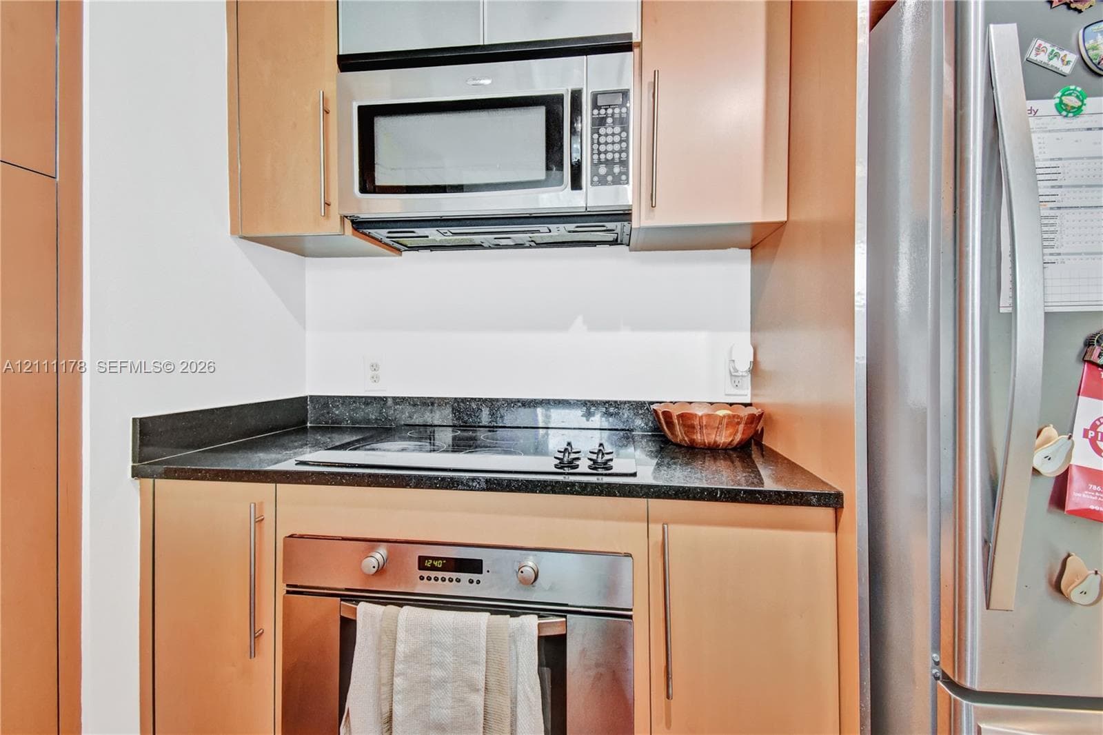 Kitchen featuring light-finish cabinetry, stone-surface countertops, stainless steel electric cooktop, built-in oven, and over-the-range microwave
