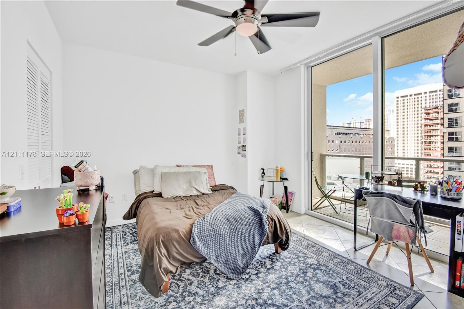Floor-to-ceiling glass sliding doors, private balcony, tile flooring, and ceiling fan