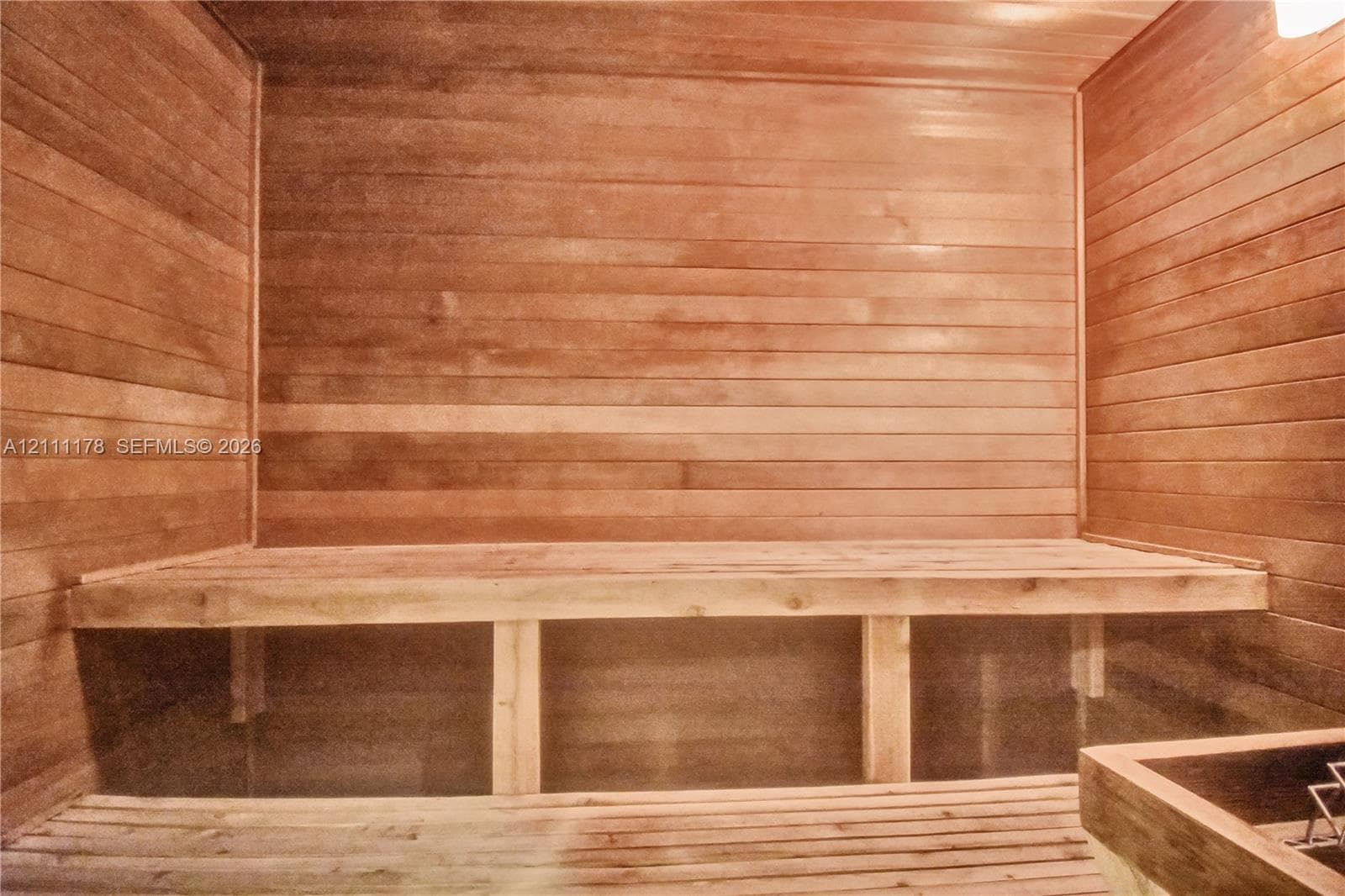 Sauna featuring tongue-and-groove wood paneling, multi-level wood bench seating, and an integrated heating unit