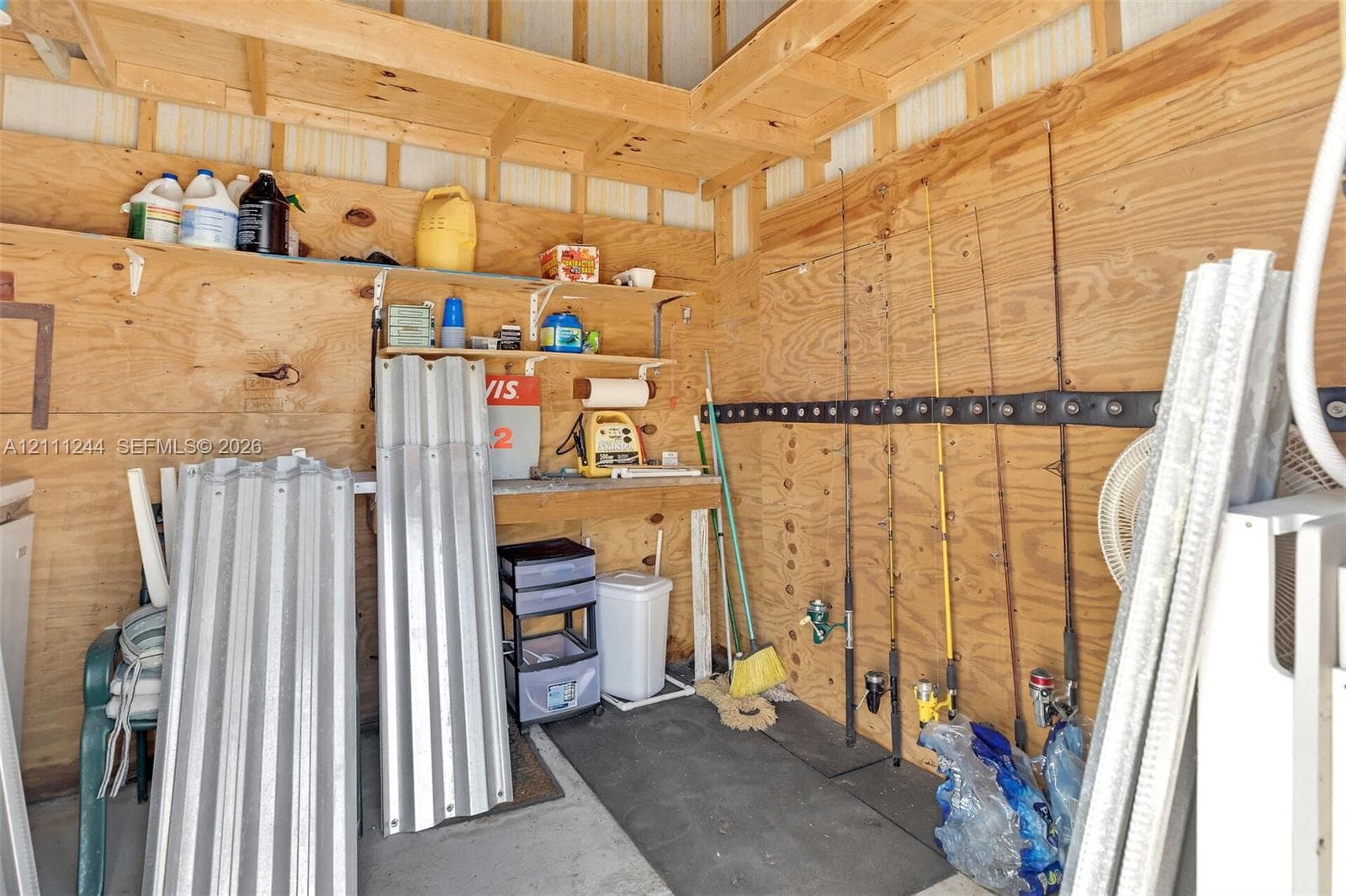 Storage structure featuring exposed plywood wall paneling, open wood shelving, and a wall-mounted rack system