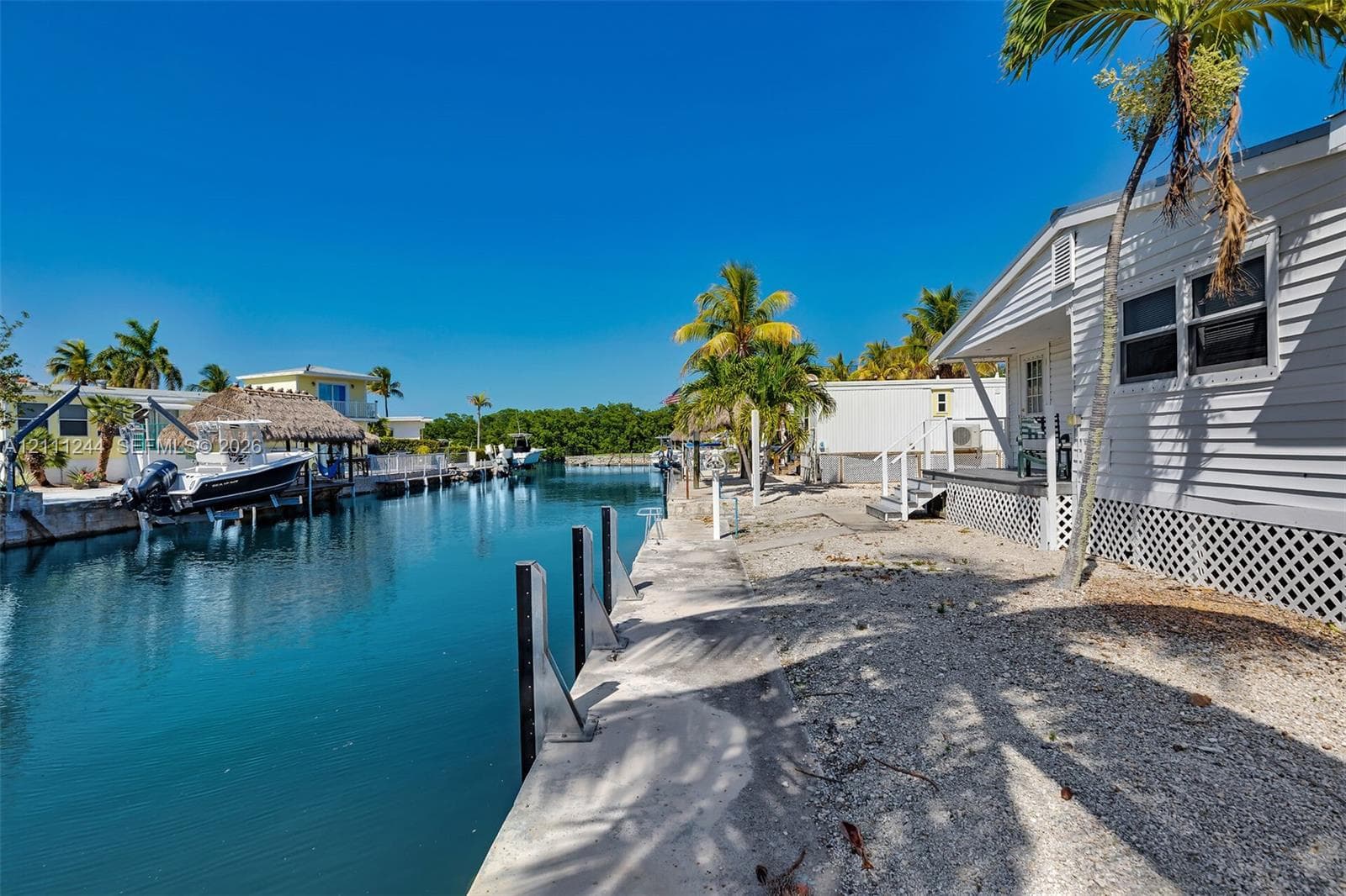 Waterfront property featuring a private concrete seawall, deep-water canal access, and exterior lattice skirting