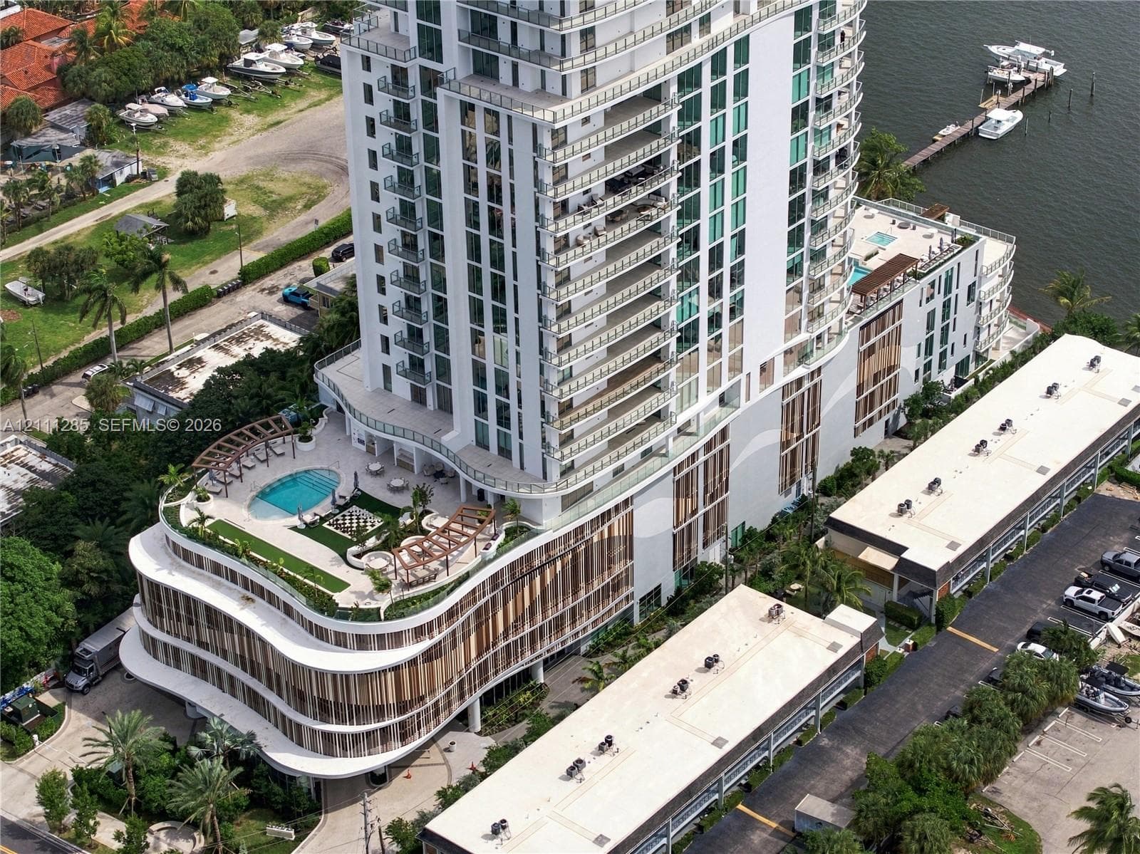 High-rise residential tower featuring a multi-level structure, wraparound balconies, an elevated swimming pool with a sprawling sun deck, and integrated waterfront access