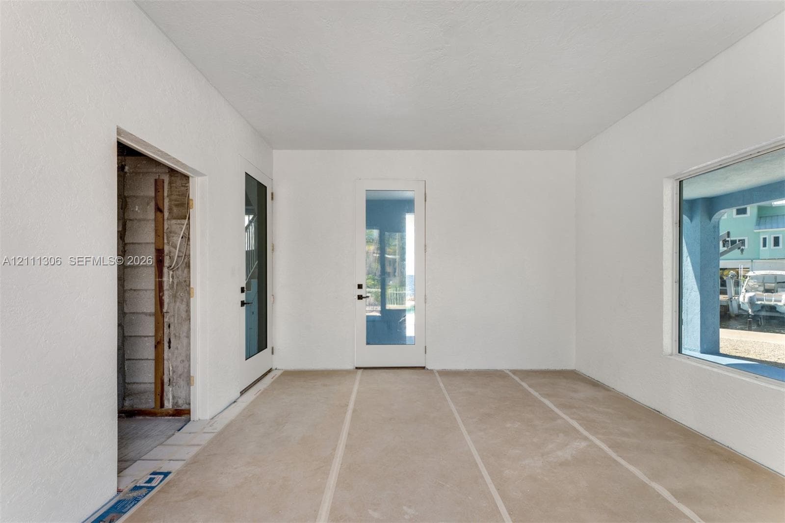 Interior space featuring smooth-finish white walls, a single-lite glass entry door, a dual-pane glass door, and a large picture window