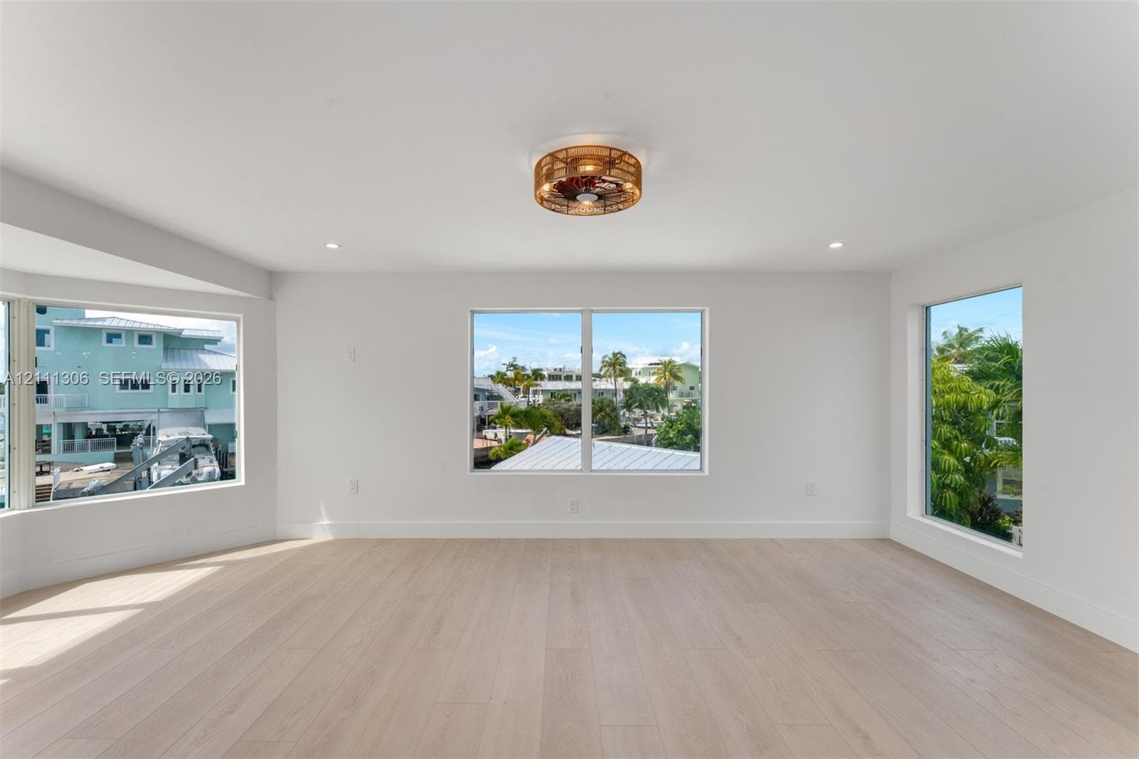 Light-filled room featuring wood-finish flooring, recessed lighting, and a circular wicker-style ceiling fixture