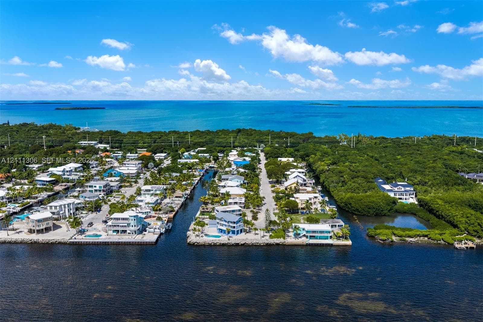 Aerial perspective of waterfront properties featuring direct canal access, seawalls, and proximity to the open ocean