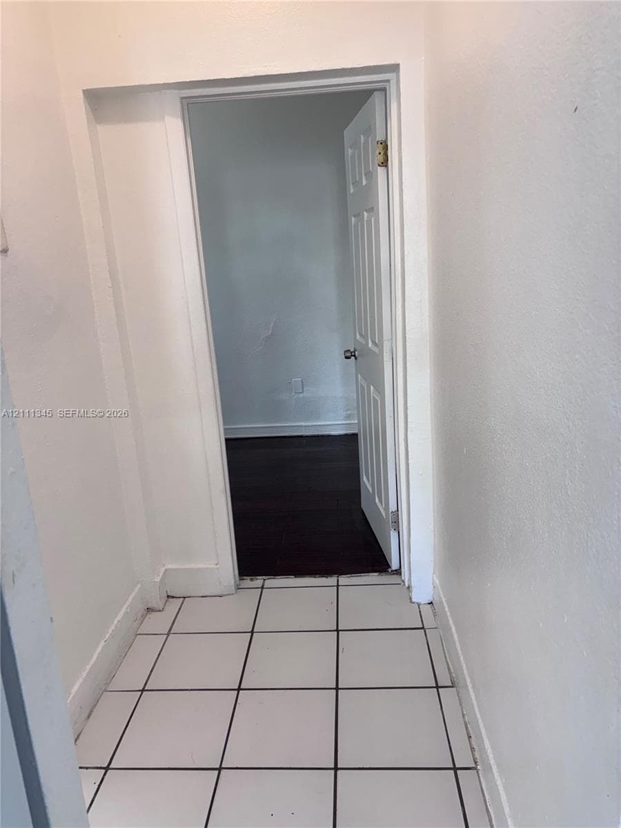 Entryway featuring white tile flooring, wood-finish flooring, and a six-panel interior door