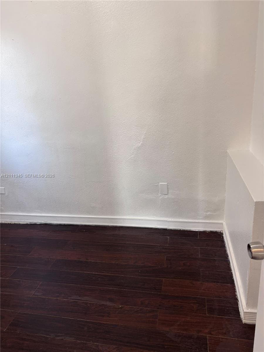 Dark-toned wood-finish flooring paired with neutral-finish walls and a structural half-wall partition